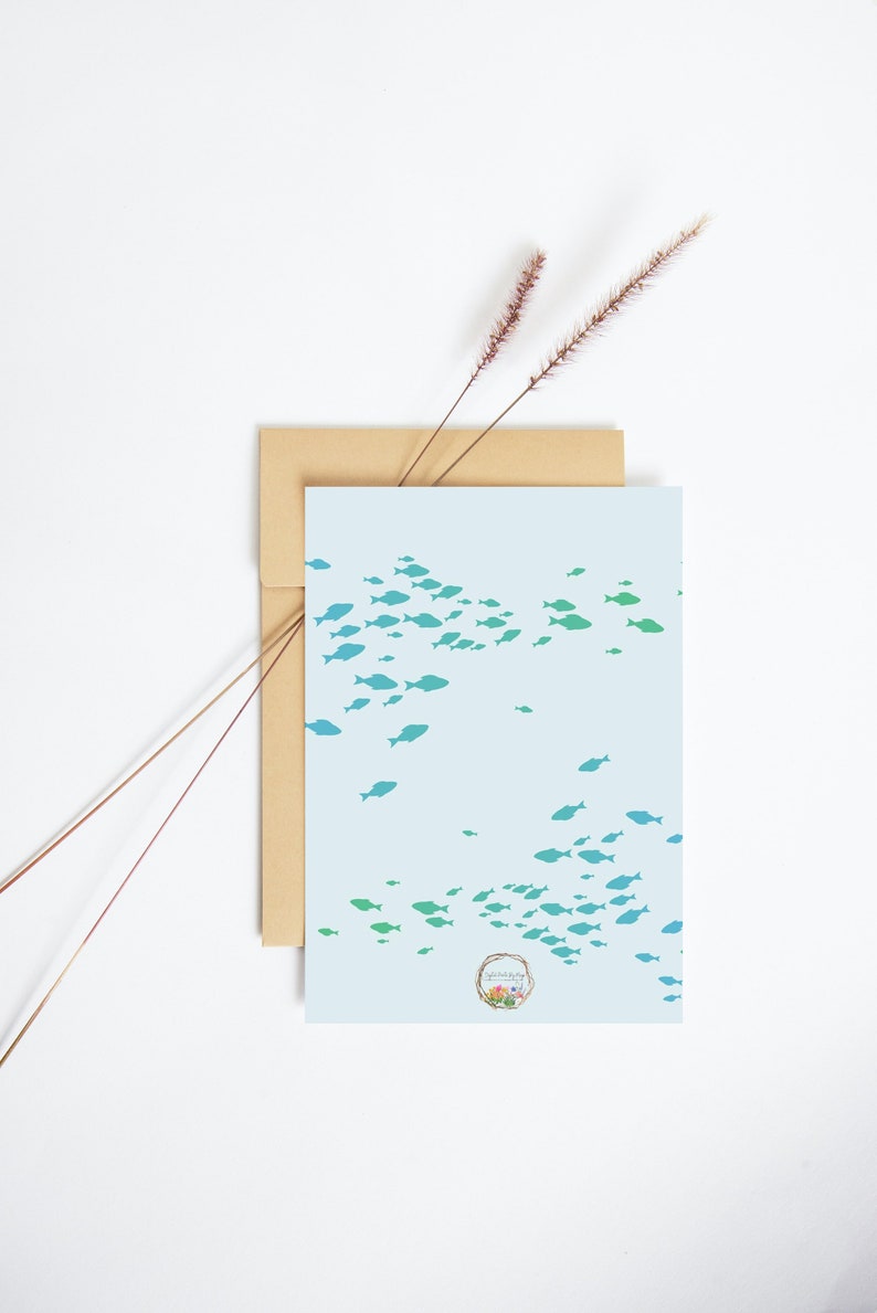 May include: A light blue card with a school of teal and blue fish swimming in a pattern. The card has a small floral logo in the bottom right corner that says "Simply Made Pretty".