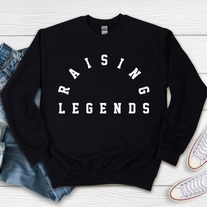 May include: Black sweatshirt with white text that reads "Raising Legends" in an arc shape.