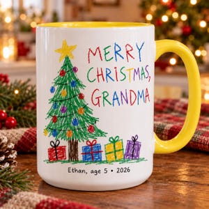 May include: A white ceramic mug with a bright yellow handle and interior. The front features a colorful crayon-style drawing of a Christmas tree with ornaments, gifts, and the text "MERRY CHRISTMAS, GRANDMA" and "Ethan, age 5 • 2026".