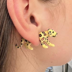 Könnte beinhalten: Ein Set aus drei Keramikbechern mit gesprenkelter, matter Oberfläche. Die Becher sind in Creme-, Hellgrau- und Dunkelgrautönen gehalten. Jeder Becher hat ein schlichtes, minimalistisches Design.