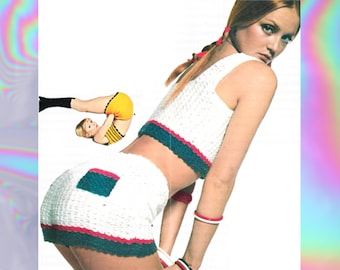 May include: A white crocheted two-piece outfit with green and red trim. The top is a cropped tank top and the bottom is a pair of shorts. The outfit is shown on a model with long brown hair.