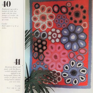 A groovy vintage retro hanging crochet flower rug from 1973 with bright pink, periwinkle blue, bright baby blue, dark blue, white, light purple and magenta flowers with palm plants nearby