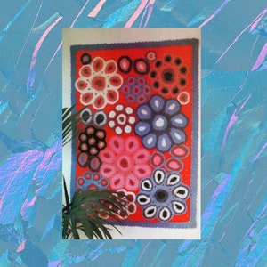 Puede incluir: Un tapiz de pared de ganchillo colorido con un fondo rojo y varios tonos de flores rosas, azules y negras. Las flores están dispuestas en un patrón circular.