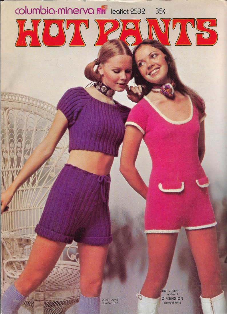 May include: Two women modeling knitted shorts and a jumpsuit. The woman on the left is wearing a purple knitted crop top and matching shorts. The woman on the right is wearing a pink knitted jumpsuit with white trim. The image is from a vintage knitting pattern leaflet.