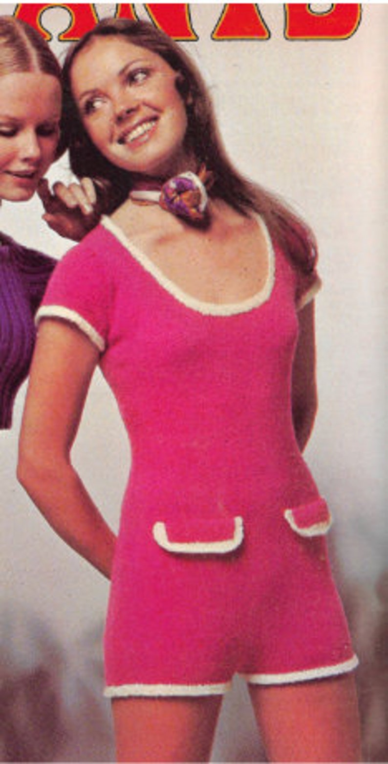 May include: A pink knitted jumpsuit with white trim. The jumpsuit has a scoop neck and short sleeves. It features two patch pockets on the front.