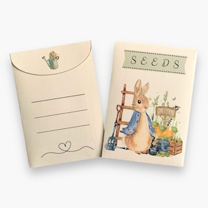 May include: A brown paper seed packet with a watercolor illustration of a rabbit holding a trowel and standing next to a ladder. The packet has a green banner that says "SEEDS" and a sign that says "GARDEN".