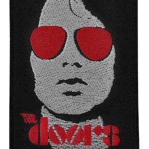 May include: A black and red embroidered patch featuring a stylized image of a person wearing sunglasses with the text "The Doors" below.