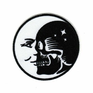 Op de afbeelding: Een ronde patch met een zwarte schedel en sterren aan de rechterkant, en een witte maan met een gezicht aan de linkerkant. De patch heeft een zwarte rand en is bedoeld voor kleding of accessoires.