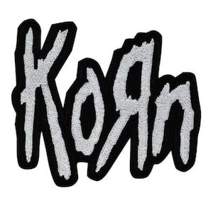 Può includere: Toppa ricamata con il nome della band "Korn" in lettere bianche stilizzate. Il testo è delineato in nero, creando un forte contrasto. La toppa ha un bordo nero ed è progettata per essere stirata o cucita su tessuto.
