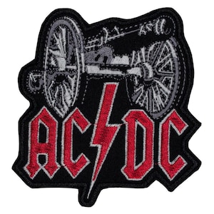 May include: A black embroidered patch featuring a grey cannon graphic at the top and the red text AC/DC with a central red lightning bolt symbol. The design is outlined in black thread with a die-cut shape following the contour of the artwork.