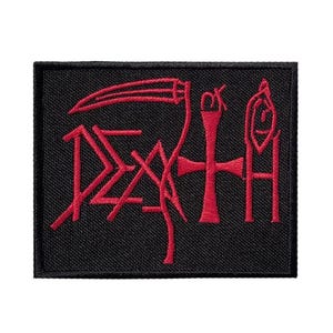 May include: A rectangular black embroidered patch featuring the word DEATH in red thread. The letter A is stylized as a scythe, the T is replaced by a cross, and the H incorporates a small circular symbol at the top. The edges are finished with black stitching.