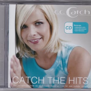 Può includere: Custodia del CD con C.C. Catch con capelli biondi e un top blu. Il titolo dell'album "Catch the Hits" è visualizzato in grandi lettere bianche. Il CD include "Greatest Hits" e "New Megamixes".