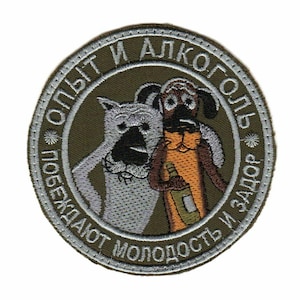Puede incluir: Un parche bordado verde con dos perros de dibujos animados. El texto en el parche dice "Опыт и алкоголь побеждают молодость и задор".