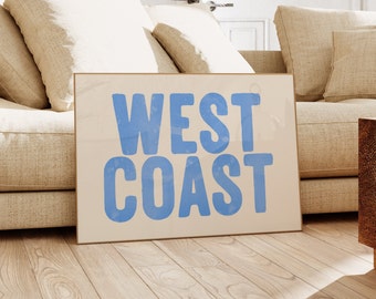 Puede incluir: Un sofá beige con almohadas y un póster que dice "WEST COAST" en letras azules sobre un fondo blanco.