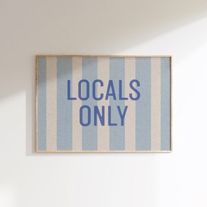 Op de afbeelding: Een ingelijst print met een blauw-wit gestreepte achtergrond en de tekst "LOCALS ONLY" in blauw.