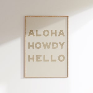 Puede incluir: Una impresión enmarcada con las palabras "ALOHA HOWDY HELLO" en color beige sobre un fondo crema.