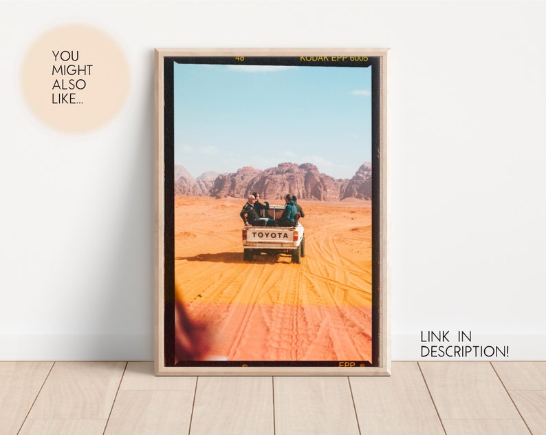 May include: A vintage photograph of a white Toyota pickup truck driving through a desert landscape. The truck is carrying three people and has a 'TOYOTA' logo on the back. The photo is framed in a wooden frame.
