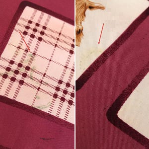 May include: Close-up of a silk scarf with a plaid pattern in burgundy, cream, and black. The scarf has a border of solid burgundy. A small illustration of a brown animal is visible on the cream-colored section.