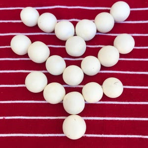 Pode incluir: Um fundo de tecido listrado branco, vermelho e branco com um arranjo simétrico de 19 bolas redondas brancas.