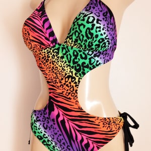 May include: Rainbow zebra and leopard print one-piece swimsuit with a cut-out design and black tie strings.