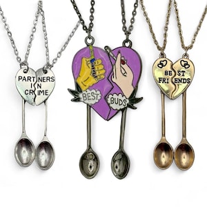 May include: Two matching necklaces with spoons and broken heart pendants. One pendant says "Partners in Crime" and the other says "Best Buds" with a cartoon image of two hands holding a syringe and a cigarette.
