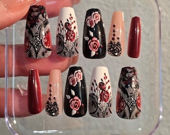 May include: A set of ten false nails with a black and white lace design and red roses. The nails are in a clear plastic case.