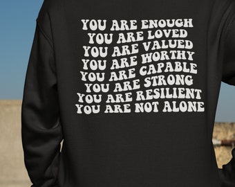 May include: Black sweatshirt with white text on the back that reads "You are enough, You are loved, You are valued, You are worthy, You are capable, You are strong, You are resilient, You are not alone."