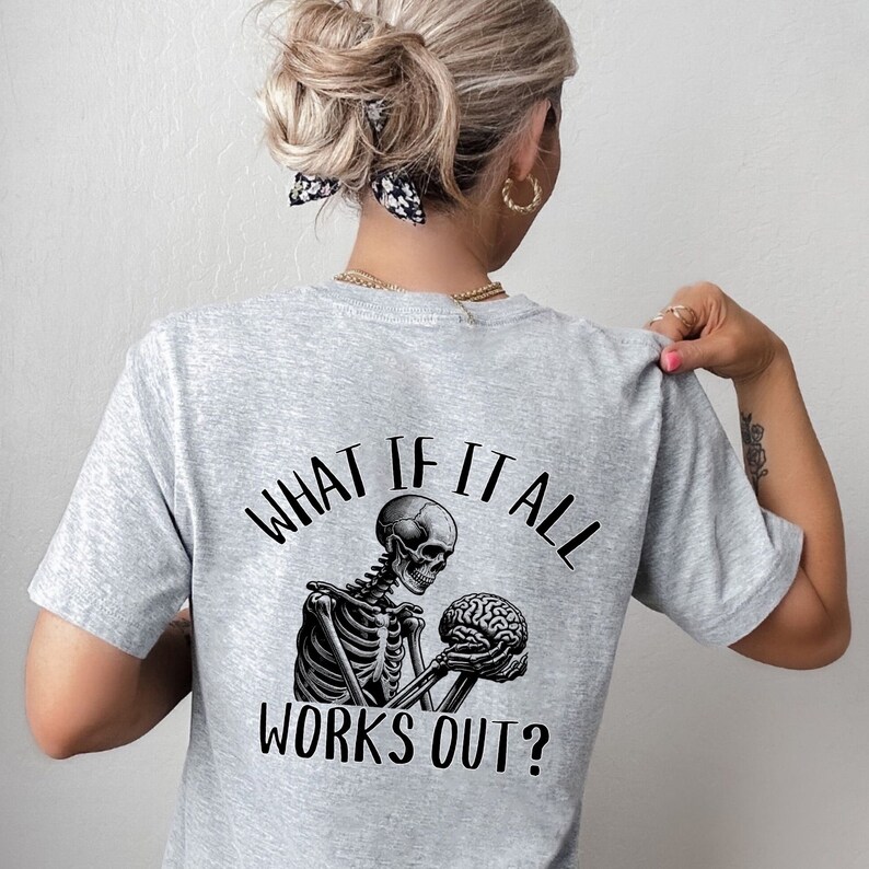 Op de afbeelding: Grijs T-shirt met een skelet dat een hersenen vasthoudt en de tekst "What if it all works out?"