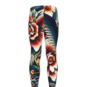 May include: Full-length leggings featuring a vibrant, multi-colored floral and avian print. The design showcases large red, orange, and white flowers against a dark background, interspersed with blue and black bird feathers and green foliage details.