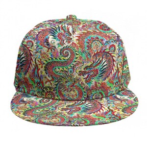 Può includere: Un cappellino da baseball a tesa piatta con una vivace stampa all-over di draghi. Il design presenta draghi rossi, verdi e blu su uno sfondo color crema. Il cappellino ha una corona strutturata e una visiera piatta.