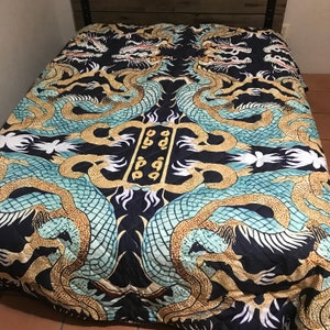 May include: A black, blue, and gold quilt with a repeating pattern of dragons. The quilt is quilted in a diamond pattern.