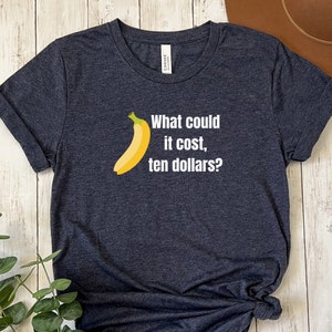 May include: A dark heather grey t-shirt with a white graphic of a banana and the text "What could it cost, ten dollars?"