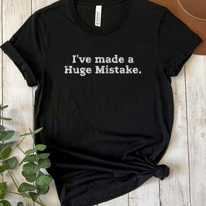 May include: Black t-shirt with the text "I've made a Huge Mistake." printed in white on the front.