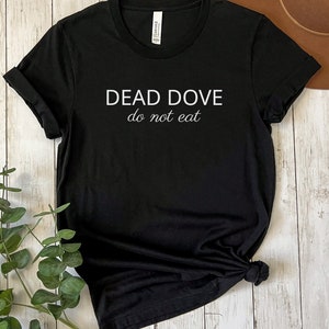 May include: Black t-shirt with white text that reads "DEAD DOVE do not eat".