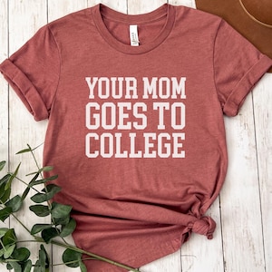 May include: A maroon t-shirt with the text "Your Mom Goes To College" printed in white.