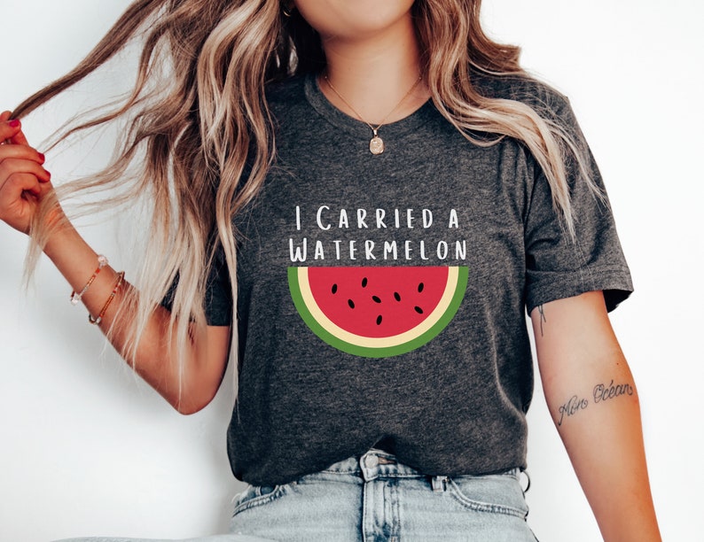 Może przedstawiać: Szary t-shirt z napisem "I carried a watermelon" i grafiką czerwonego plastra arbuza z czarnymi pestkami i zieloną sk&oacute;rką.