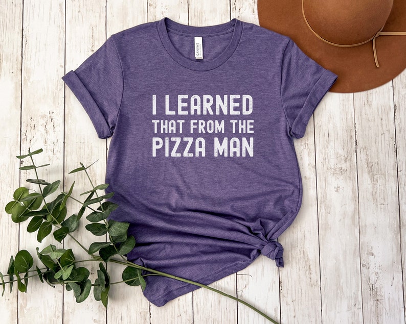 May include: A purple t-shirt with the text "I LEARNED THAT FROM THE PIZZA MAN" printed in white.