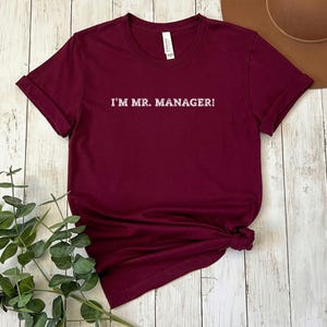 May include: Burgundy t-shirt with white text that reads "I'M MR. MANAGER!"