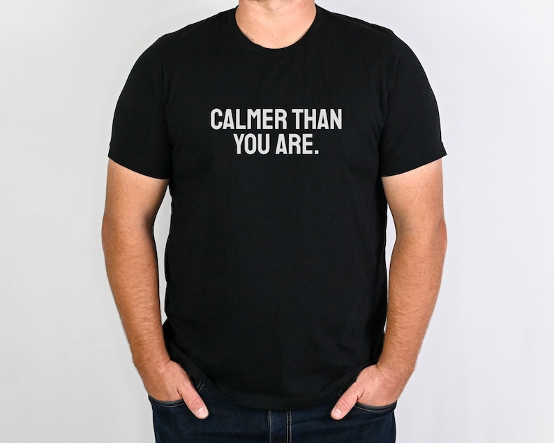 May include: A black t-shirt with the text "CALMER THAN YOU ARE." printed in white.