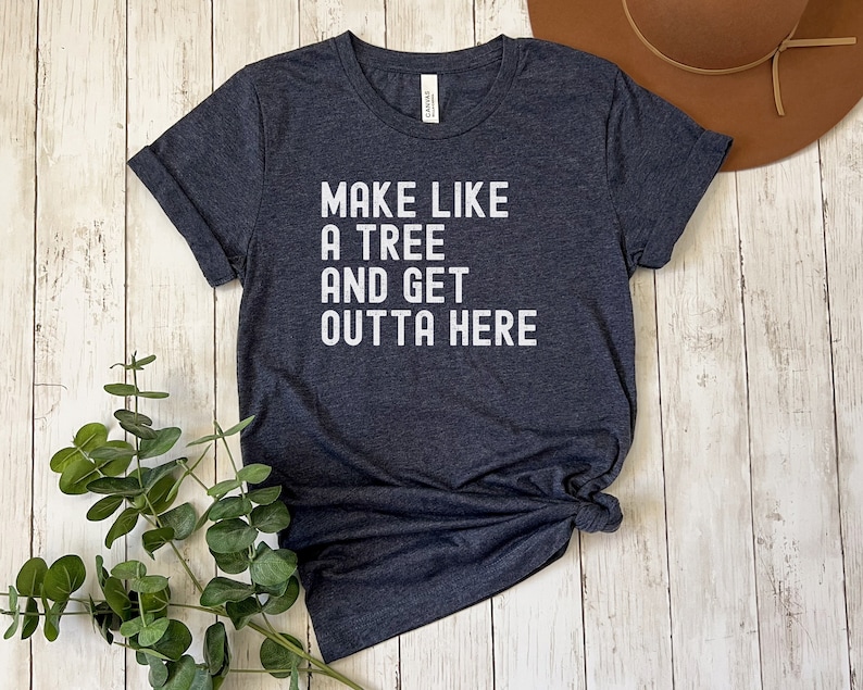 May include: A dark blue t-shirt with white text that reads "Make like a tree and get outta here".