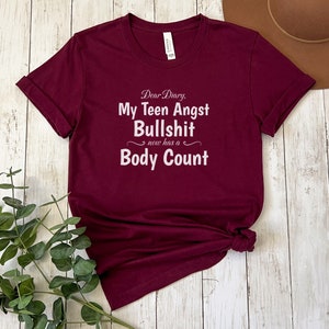 May include: Burgundy t-shirt with white text that reads "Dear Diary, My Teen Angst Bullshit now has a Body Count."
