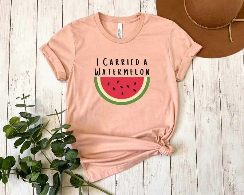 Może przedstawiać: R&oacute;żowy t-shirt z napisem "Niosłem arbuza" i grafiką plasterka arbuza.