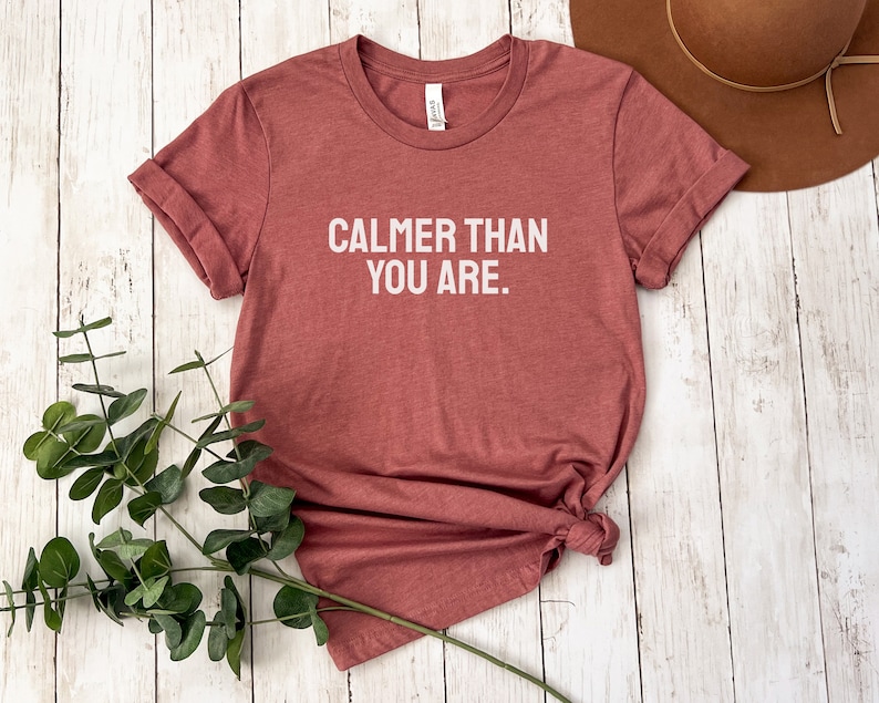 May include: A maroon t-shirt with the text "Calmer than you are." printed in white.