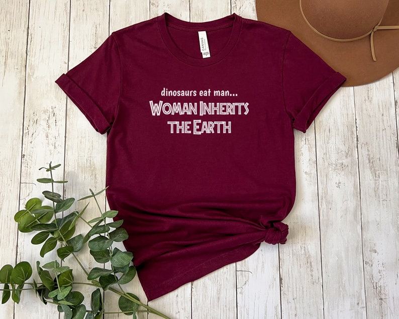 Peut inclure: T-shirt bordeaux avec un texte blanc qui dit "dinosaurs eat man... WOMAN INHERITS THE EARTH"