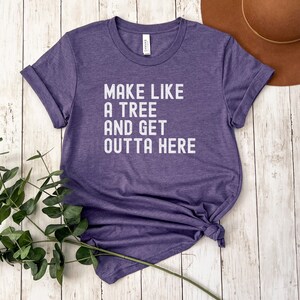 May include: Purple t-shirt with the text "Make like a tree and get outta here" printed in white.