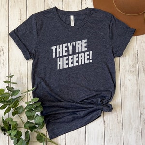 K&ouml;nnte beinhalten: Ein dunkelgraues T-Shirt mit dem Aufdruck "They're Heeeeere!" in Wei&szlig;.