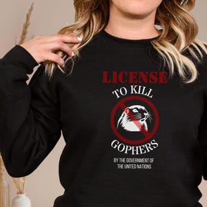May include: Black sweatshirt with a red graphic that says "License to Kill Gophers" with a red circle and a line through it, and a white gopher inside the circle. The text below the graphic says "By the Government of the United Nations."
