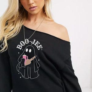 May include: Black off-the-shoulder sweatshirt with a graphic of a ghost holding a pink drink and the text "BOO-JEE".