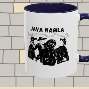 May include: White ceramic coffee mug with a blue rim and handle. The mug features a black and white illustration of four people dancing with the text "JAVA NAGILA" above them.