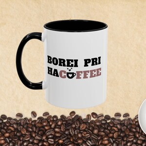 May include: White ceramic mug with a black rim and handle. The mug has black text that reads "BOREI PRI HACOFFEE" with a small brown coffee cup icon.